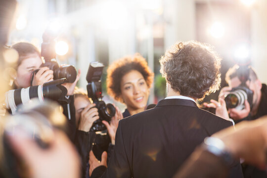 Celebrity being interviewed and photographed by paparazzi at event
