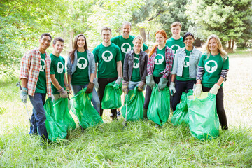Portrait of smiling environmentalist volunteers picking up trash