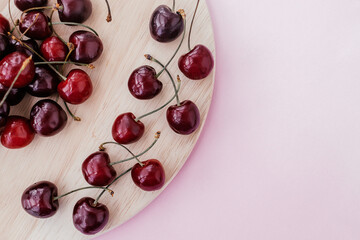  Sweet cherry on a wooden cutting board on a pink background.Summer sweet concept. Copy space for text
