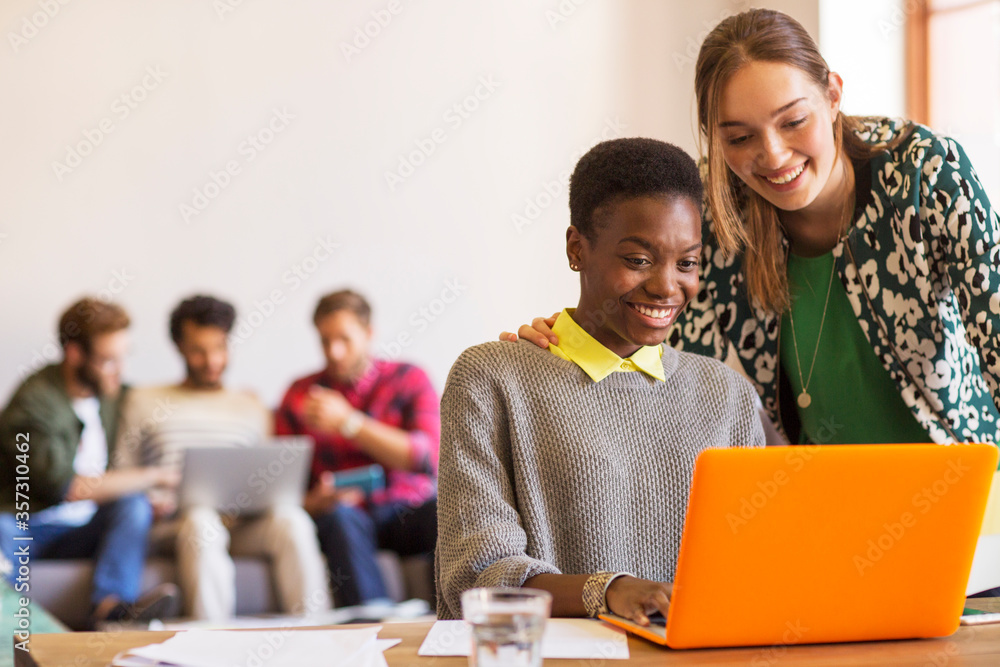 Wall mural smiling creative businesswomen working at laptop in office