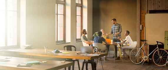 Creative businessman leading meeting at table in office