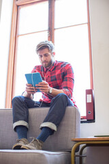 Casual businessman with headphones and digital tablet in office window