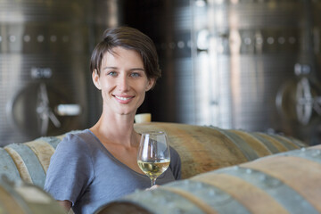 Portrait confident vintner drinking white wine in winery cellar