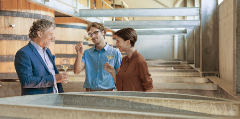 Friends barrel tasting wine in winery cellar
