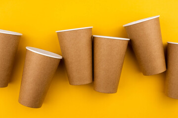 The concept of eco fast food. Three cardboard cups of eco-friendly material on a yellow background close-up with a copy space.