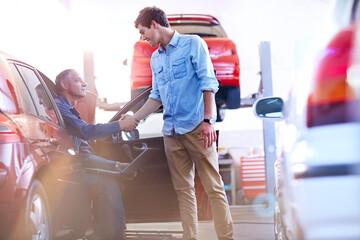 Mechanic and customer handshaking in auto repair shop - obrazy, fototapety, plakaty