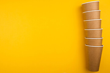 The concept of eco fast food. Three cardboard cups of eco-friendly material on a yellow background close-up with a copy space.