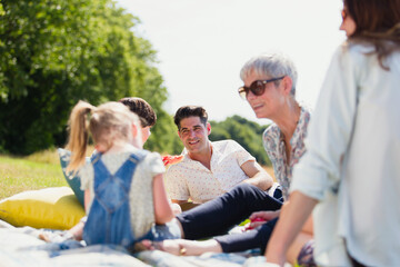 Multi-generation family relaxing on blanket in sunny field