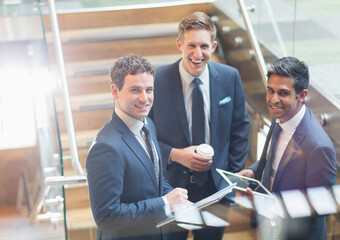 Portrait confident businessmen with coffee digital tablet on stairs