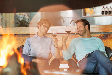 Men wine tasting at fireplace in winery tasting room