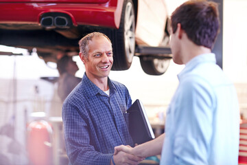Mechanic and customer handshaking in auto repair shop
