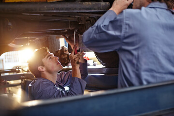 Obraz na płótnie Canvas Mechanics working under car in auto repair shop