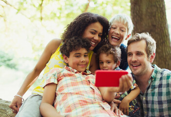 Multi-generation family taking selfie with camera phone in woods - Powered by Adobe