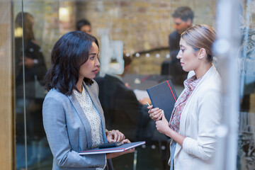Businesswomen talking outside conference room meeting