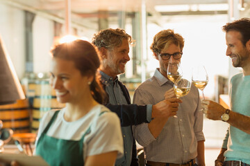 Men wine tasting white wine in winery tasting room