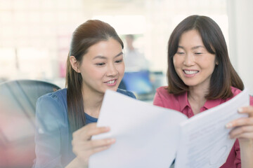Obraz premium Smiling businesswomen discussing paperwork in office