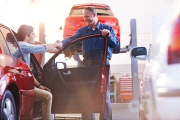 Mechanic and customer in car handshaking in auto repair shop - obrazy, fototapety, plakaty