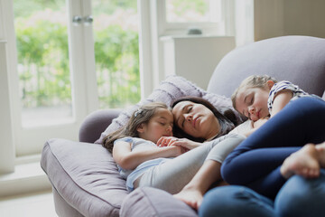 Serene mother and daughters napping on living room sofa