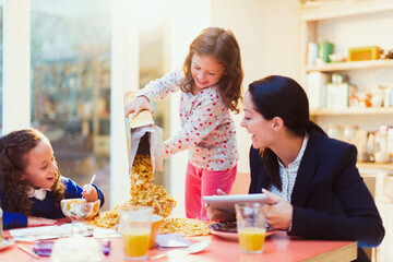 Girl pouring abundance of cereal at breakfast table