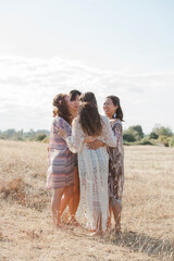 Boho women hugging in a circle in sunny rural field © Monashee Alonso/KOTO