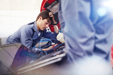 Frustrated mechanic looking down at engine in auto repair shop