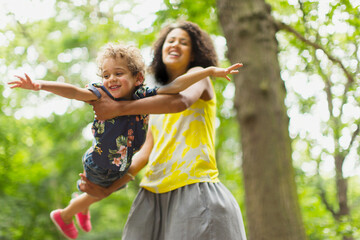 Playful mother flying son under tree