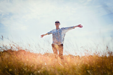Fototapeta premium Carefree senior woman running with arms outstretched in sunny field