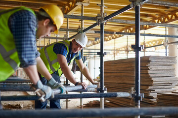 Construction workers adjusting metal bar at construction site