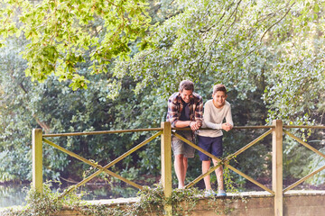 Fototapeta na wymiar Father and son on footbridge in park with trees
