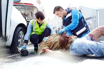 Rescue workers tending to car accident victim in road