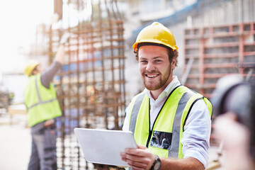 Portrait confident construction worker digital tablet at construction site - obrazy, fototapety, plakaty