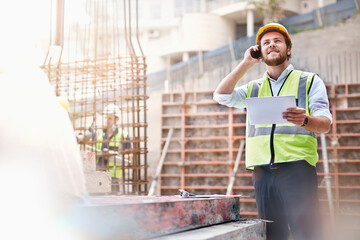 Engineer digital tablet talking on cell phone at construction site