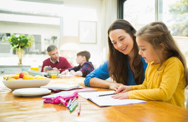 Mother and daughter doing homework at dining table