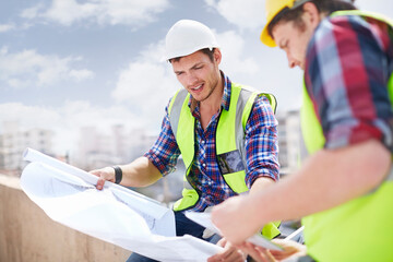 Construction worker engineer reviewing blueprints at construction site