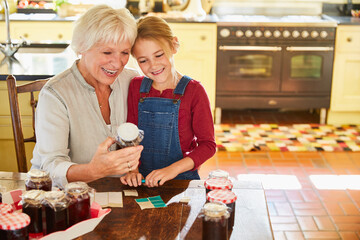 Grandmother and granddaughter canning jam in kitchen