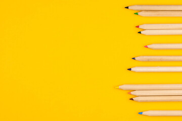 The concept of children's creativity and eco. Colored pencils made from wood on a yellow background close up with copy space