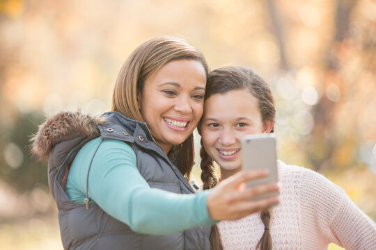 Mother and daughter taking selfie with camera phone outdoors