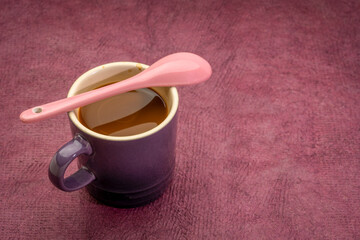 stoneware coffee cup with a spoon in purple tones against textures paper with a copy space, coffee break concept