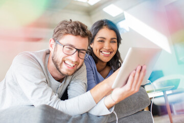 Portrait laughing couple using digital tablet