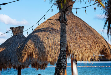 Tropical resourt beach under palm trees and beach huts in Mexico.