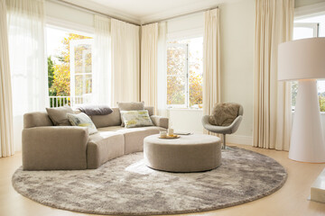 Round carpet under sofa and ottoman in living room - obrazy, fototapety, plakaty