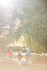 Father and sons preparing fishing rods in woods