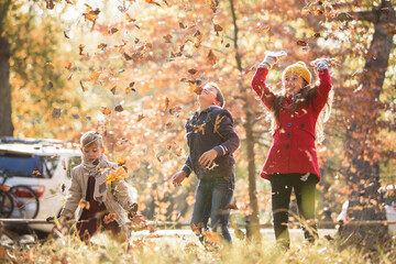 Boys and girl throwing autumn leaves overhead
