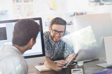 Creative designers talking between computers in office