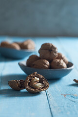 cracked walnut in front of a walnut bowl shot on blue wood 