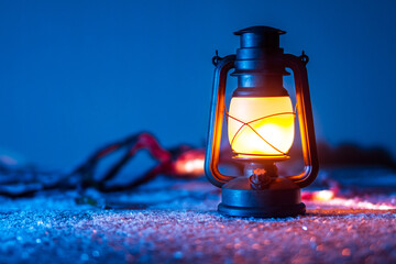 An old kerosene lamp stands on a snowy surface. In the background a monster.
