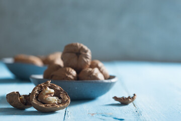 cracked walnut in front of a walnut bowl shot on blue wood 