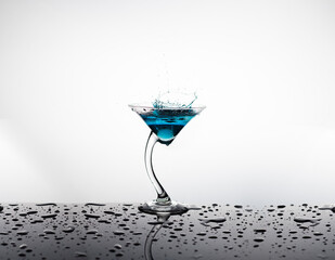 Curved stem martini glass with splashed blue drink