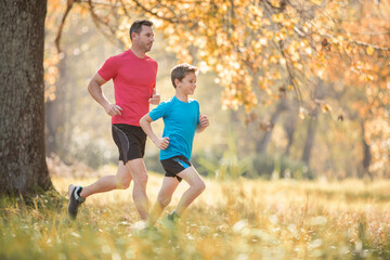 Father and son jogging in autumn park