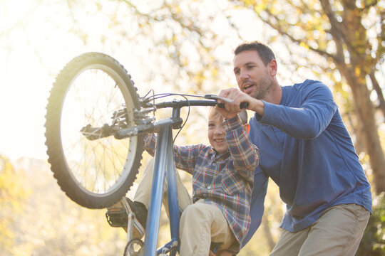 Father teaching son wheelie on bicycle